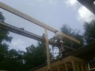 Carpenter setting a ridge beam over a new addition frame — Ice Dam Removal by Roofing Brothers in Sand Lake