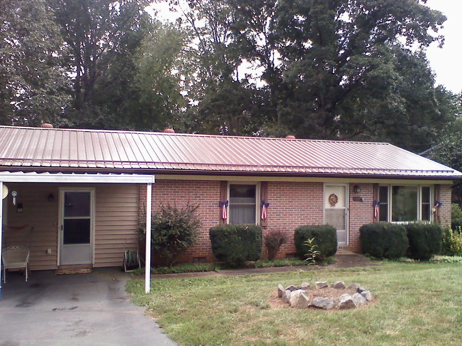 Bronze metal roof and carport on a brick ranch home — Roof Repair work by our crew in Sand Lake