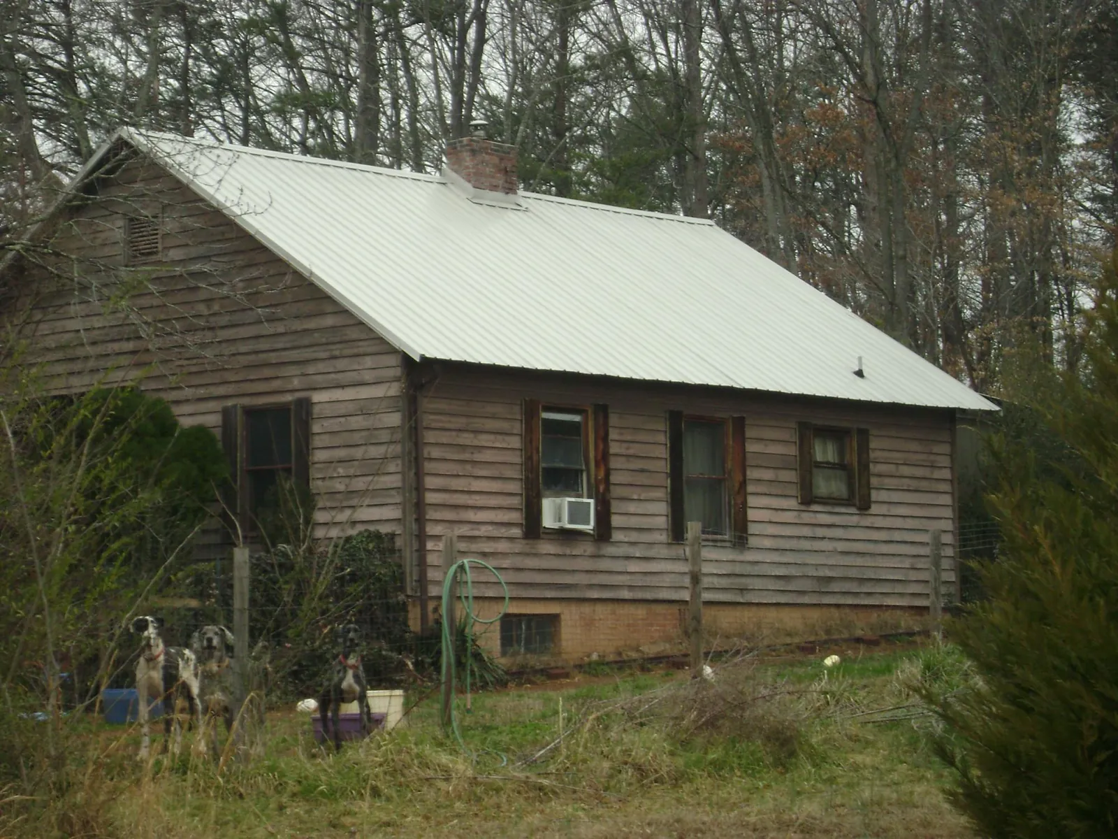 White metal roof on an old wood sided farmhouse, from a Metal Roof Installation job in Sand Lake